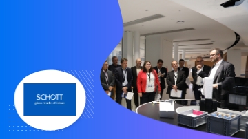 A group of people in a room with the logo of Schott AG.