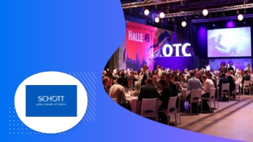 Schott logo with a photo of a large hall with tables and chairs and a large stage.