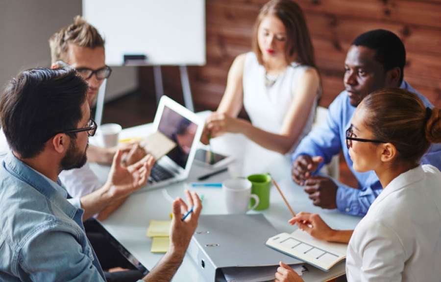 A group of business people are having a meeting and discussing something while sitting around a table.