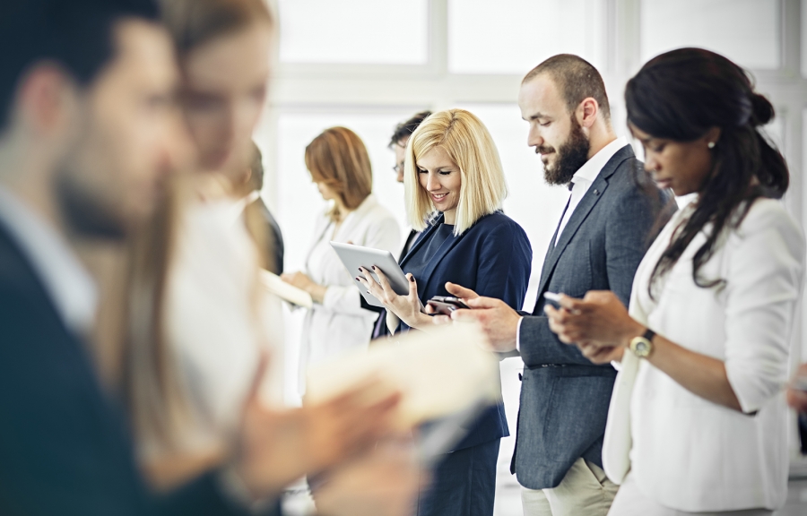 Business people in an office looking at their phones, some blurred, some focused.