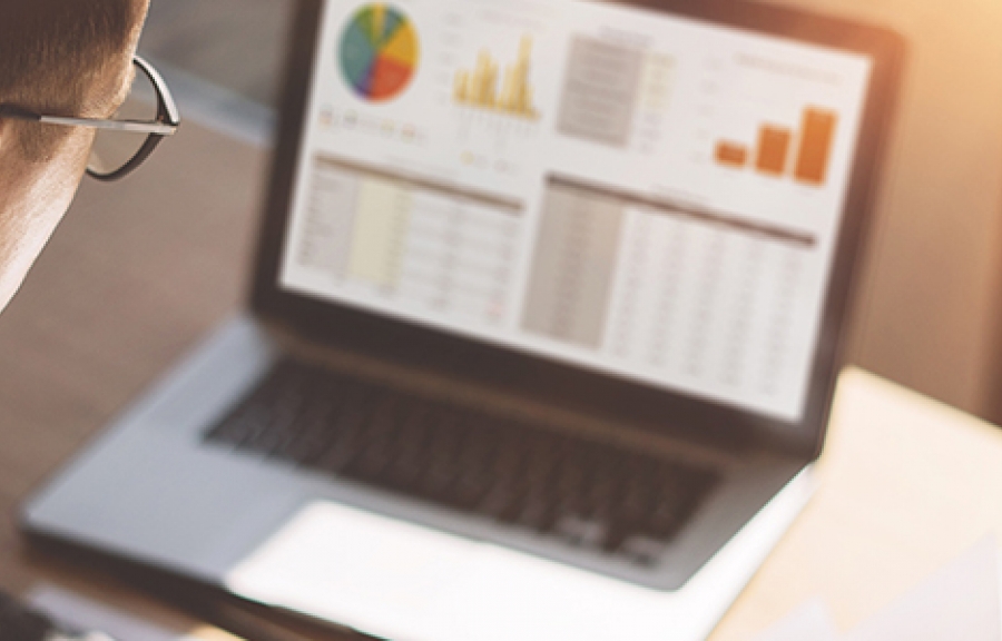 Man looking at laptop with graphs and charts on screen, possibly a customer experience survey.