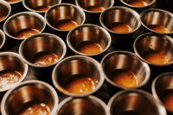 Several small stainless steel cups filled with Puerto Rican coffee on a black surface.