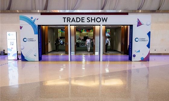 Three open doorways leading to a trade show with people in the background and a banner outside.