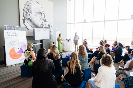 Group of women in a meeting room listening to a presentation from a field marketing manager.