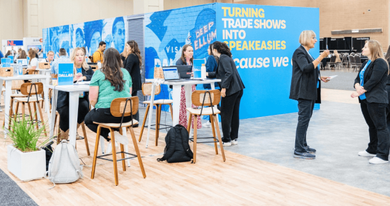 People are at the table in an event with the backdrop of "Turning Trade Shows into Speakeasies".