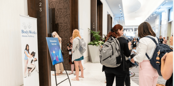 A group of people stand in a corridor with a poster, and a poster reads Body Works.