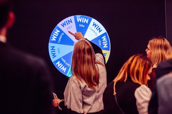 A woman spins a wheel that says win for each section and a brand for every other section.