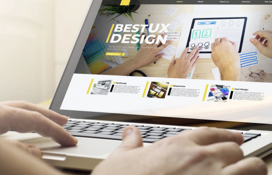 Laptop showing a website called bestuxdesign.com with hands typing on the keyboard in front of it.