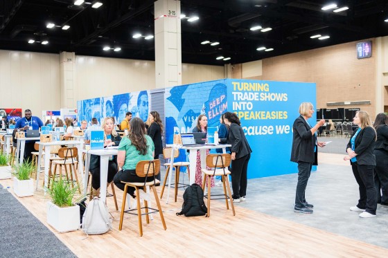 People gathered around tables at Cvent CONNECT 2024, with a "Turning Trade Shows into Speakeasies" backdrop.