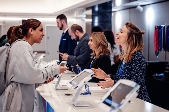 Registration desk at Cvent CONNECT Europe 2024 with two women chatting and a group of people in background.