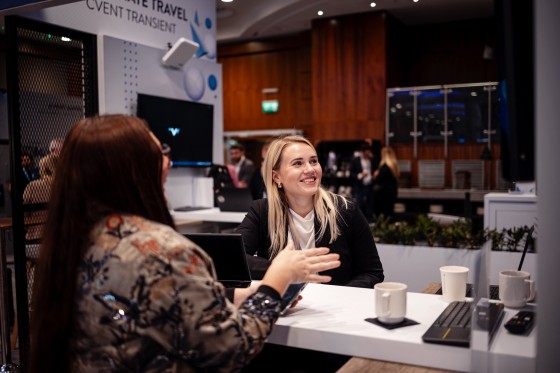 Two women networking at a trade show, with Cvent branding and event setup in the background.