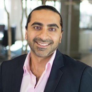 Bharrat Malhotra, a man in a black suit with a pink shirt, smiling and posing for a photo.