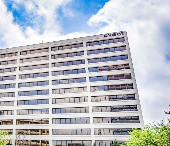 Cvent building exterior, large glass windows, and landscaping, with a blue sky background.