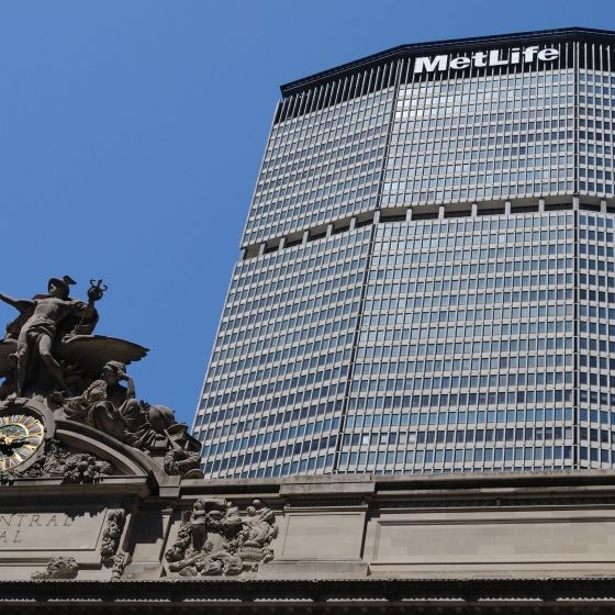 The MetLife building, a glass-clad skyscraper, stands tall above the Grand Central Terminal clock tower.