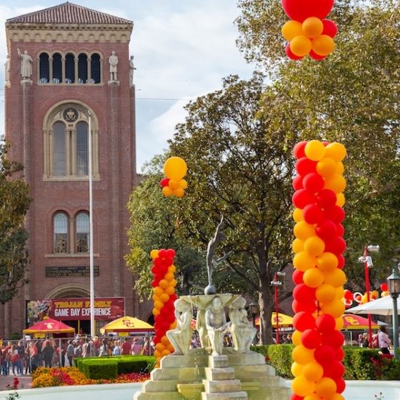 A fountain at USC's Heritage Park is surrounded by balloons and the Bovard Tower in the background.