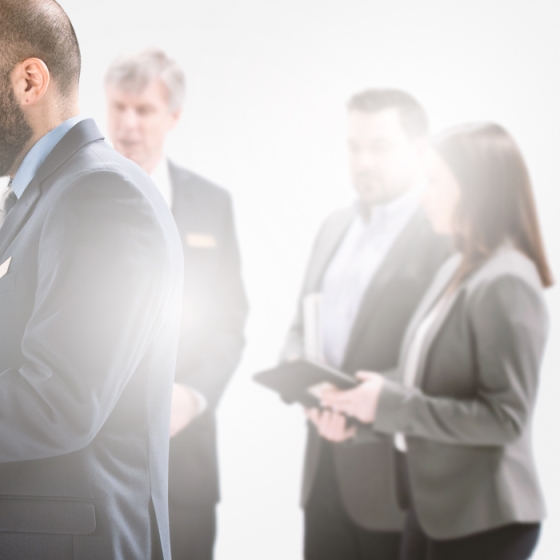 A group of people standing and smiling in a corporate office with one person holding a tablet.