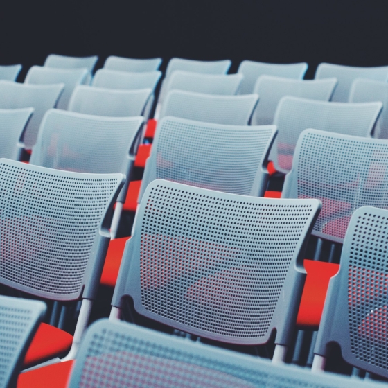 A conference hall with gray chairs and red seats arranged in rows.