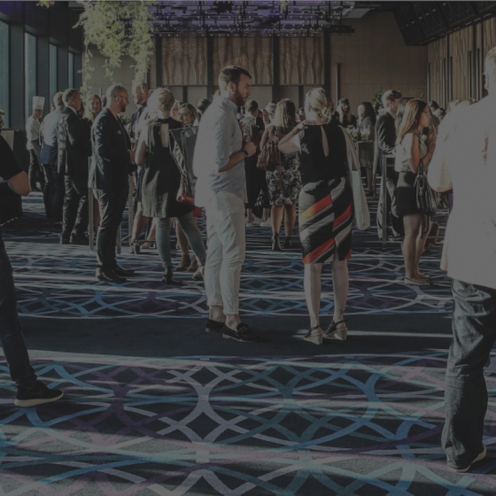 A crowd of people are gathered in the event hotel lobby background.