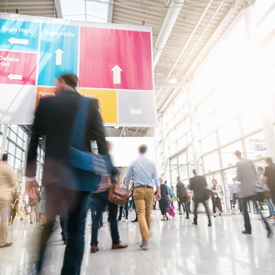 A crowd of people are walking inside a building with a sign that says "Expo Hall".