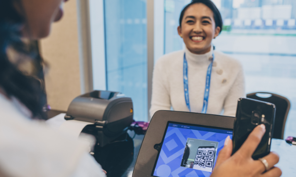 A woman scans a QR code on her phone at a registration desk in a hotel.