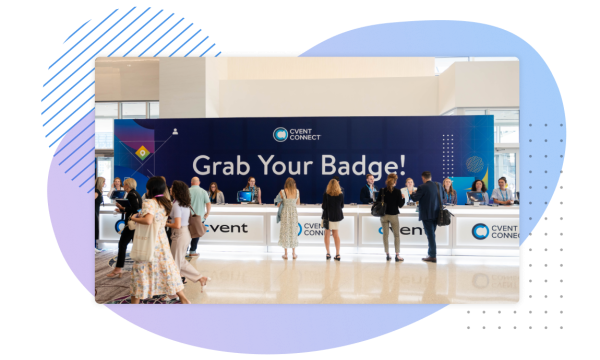 People queue up at a reception desk with a banner above them saying Grab Your Badge.