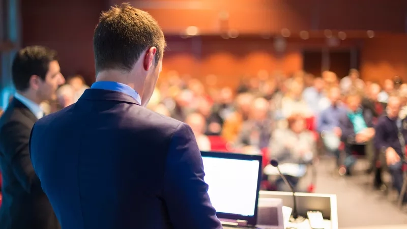 Man giving a presentation to a group of business people at a conference or seminar