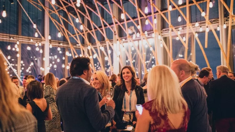 A group of people are standing in the room and enjoying a corporate event.