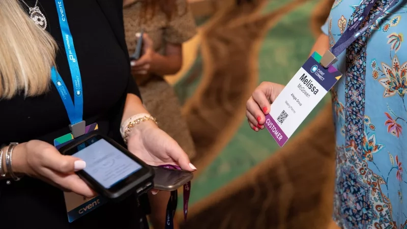 Woman scanning another woman's badge at an event with a Cvent Connect badge.