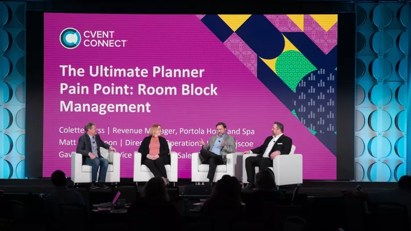 Four people on a stage at an event about room block management for planners.