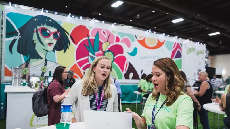 Two women are working together at an event for margaritaville.