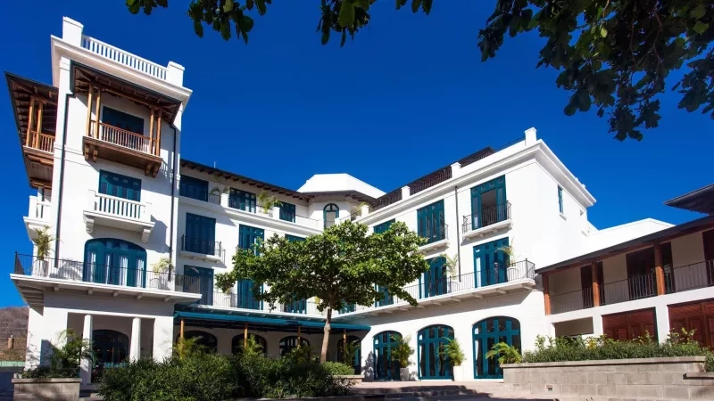 Exterior view of the Santarena Hotel with its white architecture, blue windows, and lush landscaping.