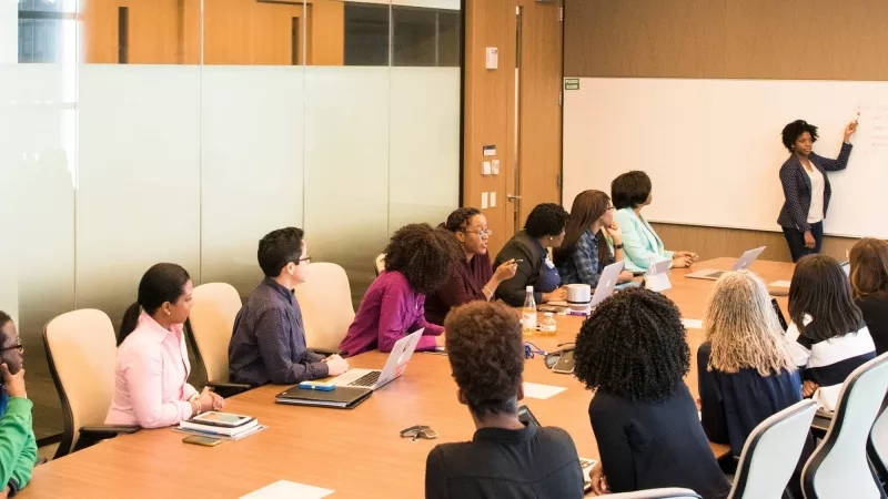 A group of women attending a conference and sitting around a table in a conference room.