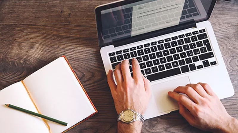 Man typing on laptop with notebook and pencil on a desk, representing the secret behind sourcing registration.
