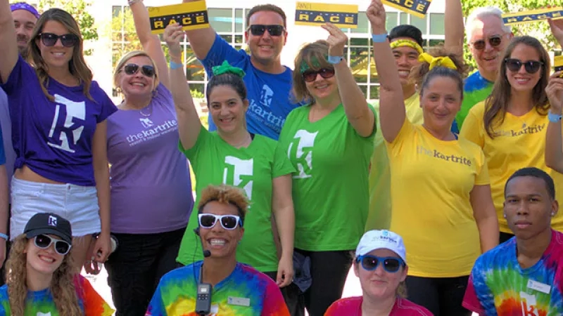 A group of people are posing for a picture with a sign saying race in the background.
