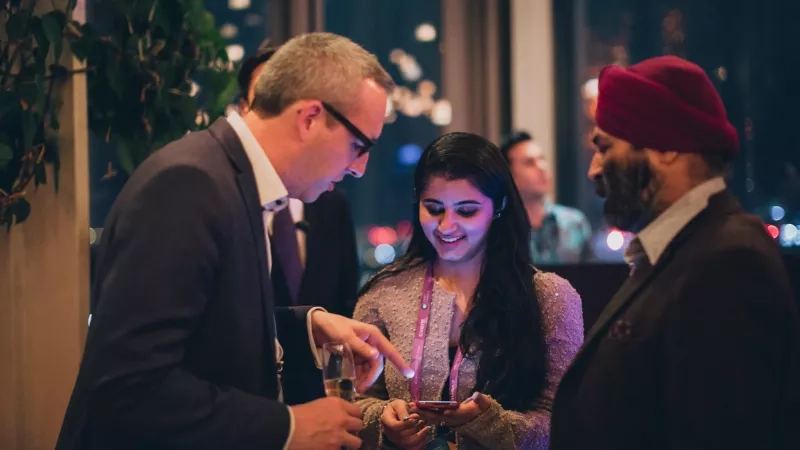 A man is showing something to a lady on a phone at a Tanushka Global Conference.