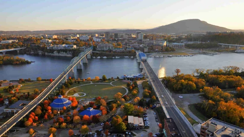 Aerial view of Chattanooga, Tennessee, with a bridge, river, and buildings at sunset.