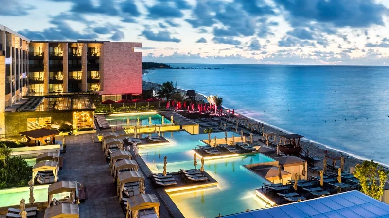 Panoramic view of Grand Hyatt Playa del Carmen with beach, pool, and modern architecture at dawn.