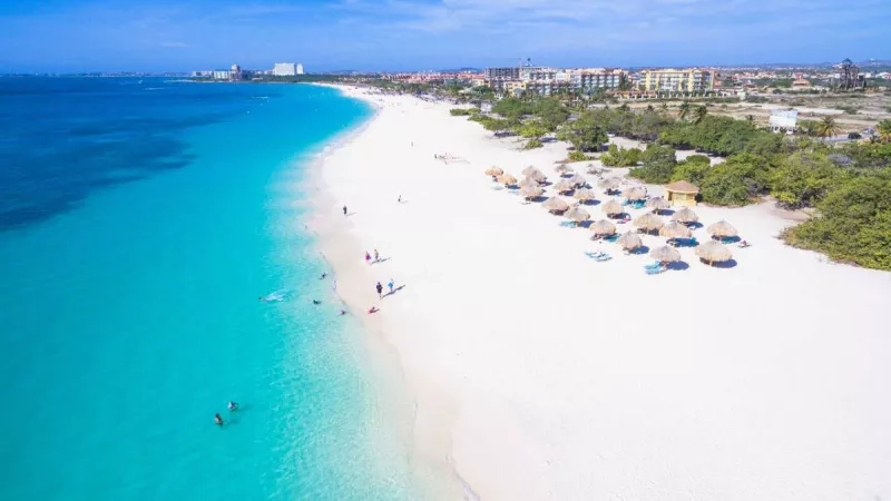 A beautiful aerial view of the sand beach with several tourists and a blue ocean at the Headliner.
