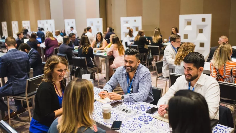 Two men and three women are sitting at a table during a conference at the Gaylord Palms Resort.