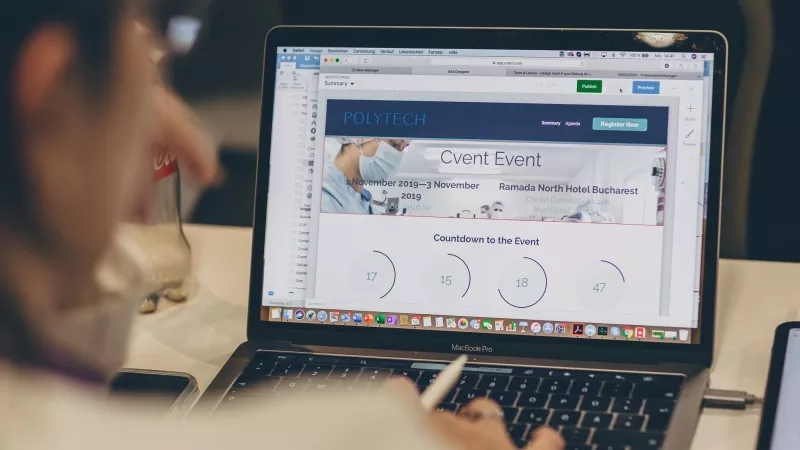 A person working on an event website in a laptop in an office space.