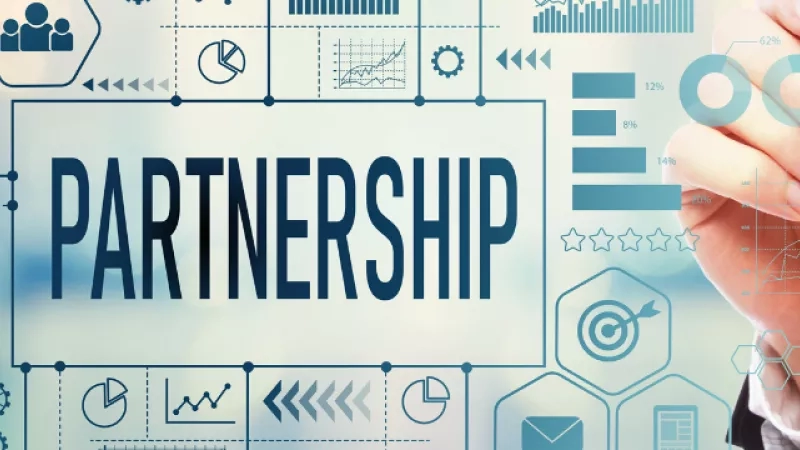 Hand holding marker on whiteboard with partnership written on it and graphs around the board.