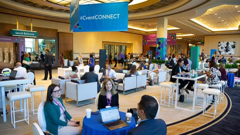 People at the convention center with laptops and banners, including one that reads "#CventCONNECT" above them.