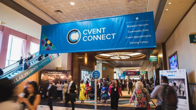 A busy event in a convention center with a Cvent Connect banner hanging from the ceiling.