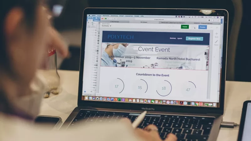 A person working on a laptop with an event website on the screen with a countdown timer.