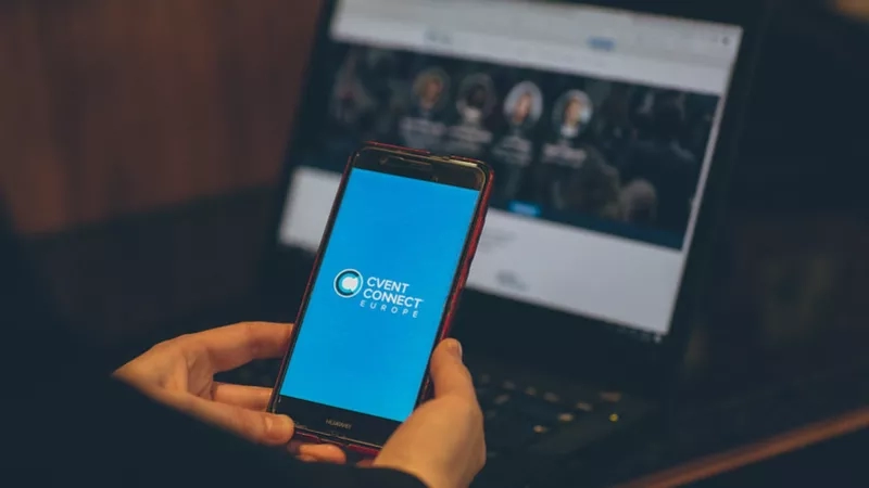 A person is using their phone to interact with the Cvent Connect Europe website on a laptop.