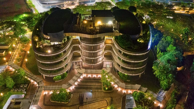 A top-down view of the Fusionopolis building with lush greenery and warm lights in the evening.
