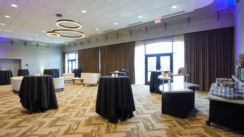 Poplar Room setup for a cocktail event with black table clothes, cocktail tables, and couches.