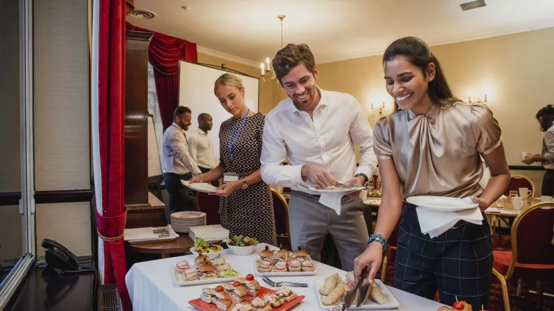 Group of business people serving food at a conference event in the banquet hall of the hotel.