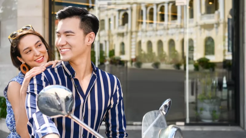 A smiling couple in front of the glass door of the Mandarin Oriental, Ho Chi Minh City.