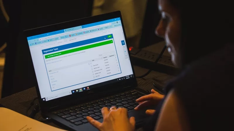 A woman using an online registration page on a laptop.